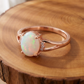 White opal rose gold ring, large three-quarter view on a tree-trunk slab