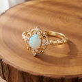 White opal baroque gold ring on a tree-trunk slab