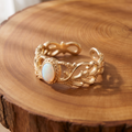 White opal leaf gold ring on a tree-trunk slab