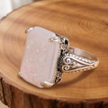 White opal antique silver ring on a tree-trunk slab
