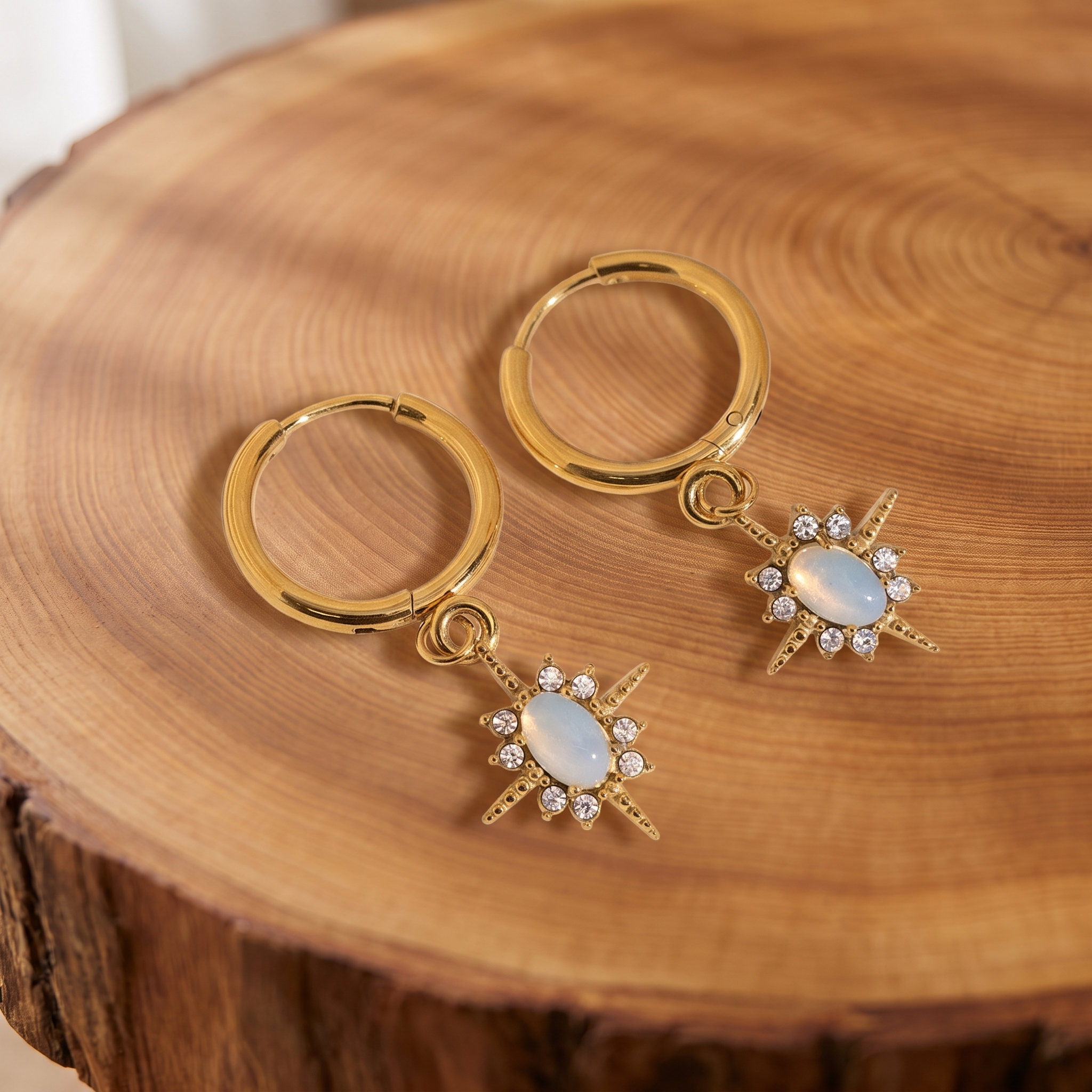 Gold opal star huggie hoop earrings on a tree trunk slab