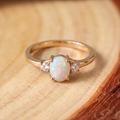 White Opal Three-Stone Gold Ring on a tree-trunk slab