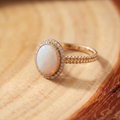 White Opal Halo Gold Ring on a tree-trunk slab