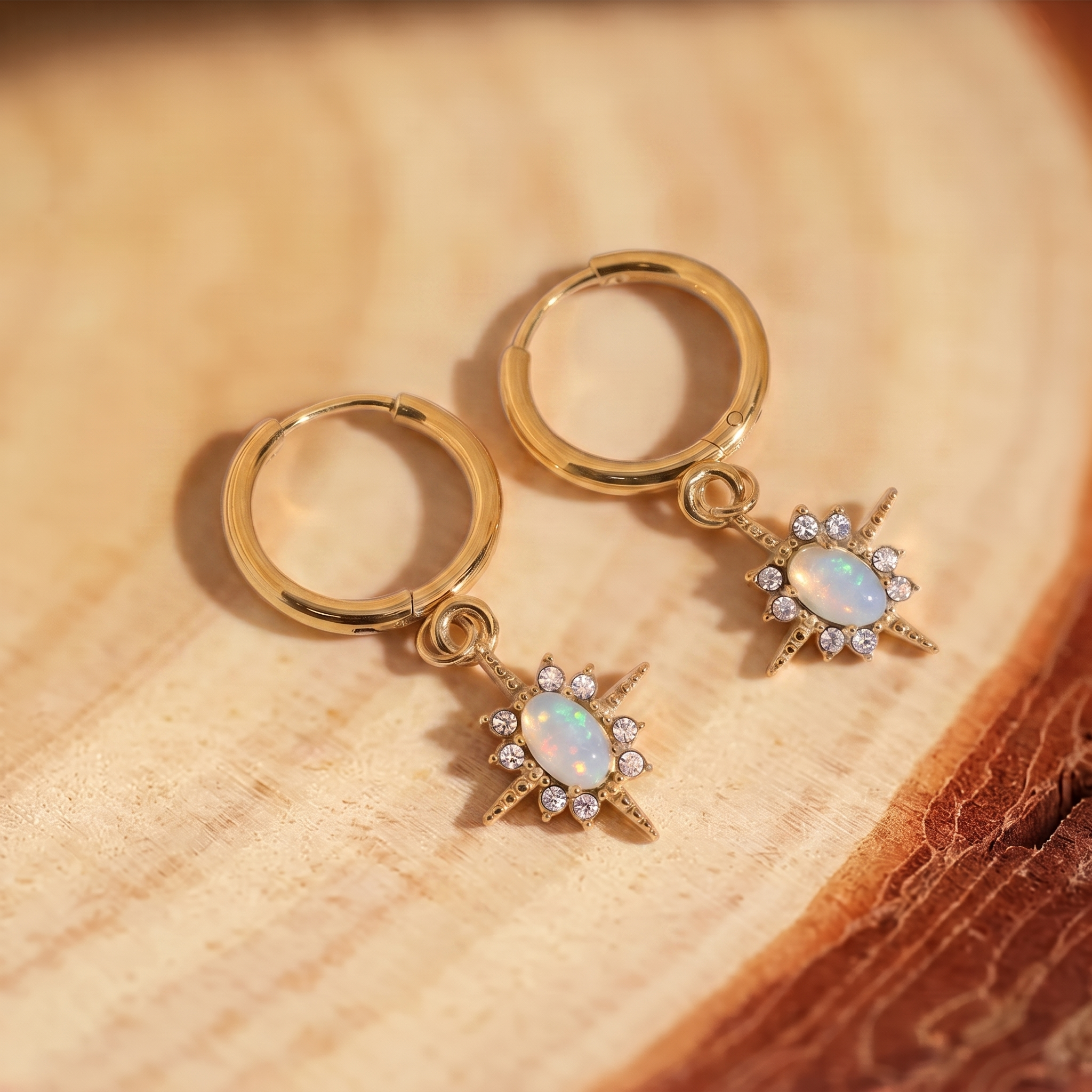 Celestial Opal Star Huggie Hoops on a tree-trunk slab