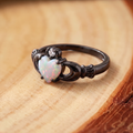 White Opal Claddagh Black Gold Ring on a tree-trunk slab