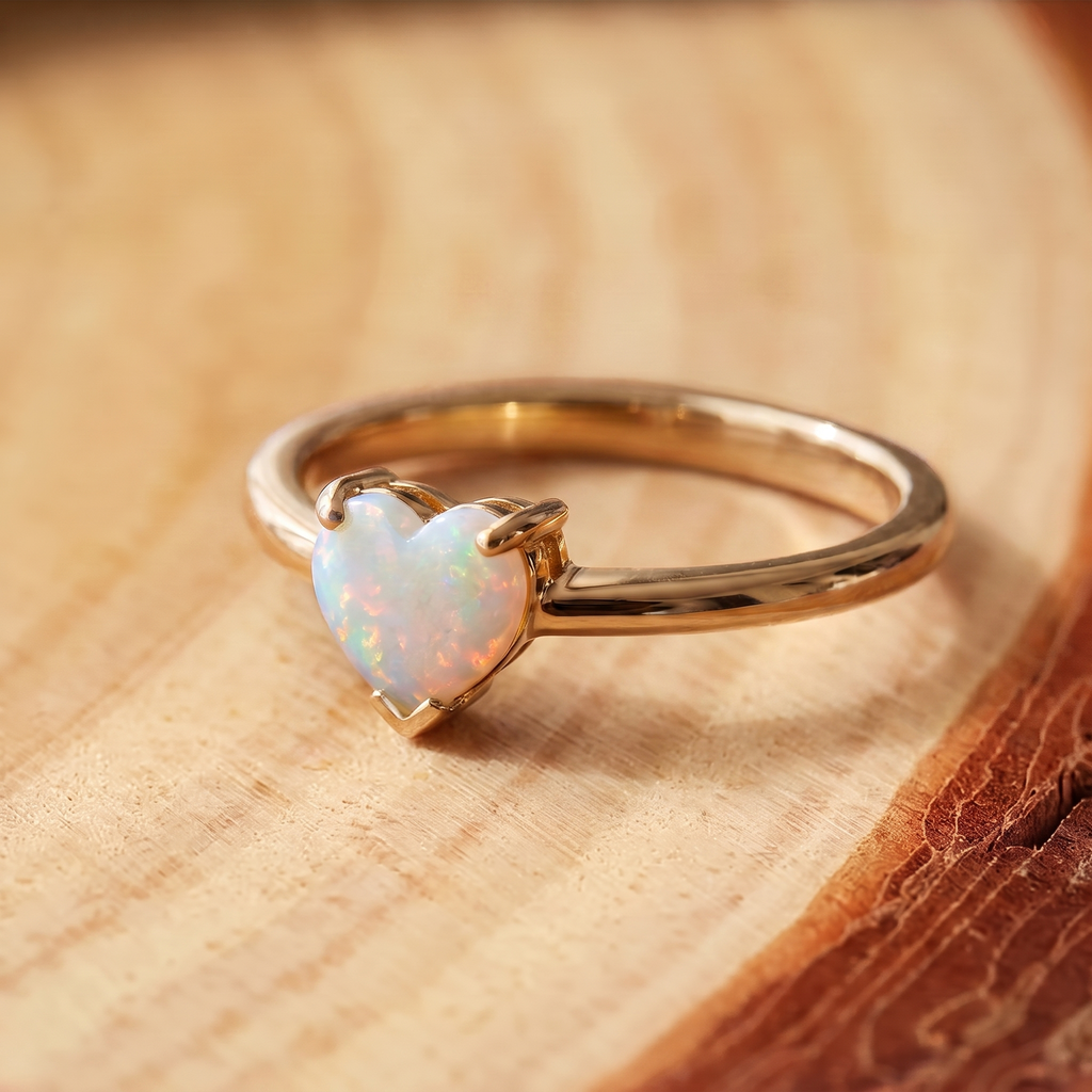 White Opal Heart Gold Ring on a tree-trunk slab